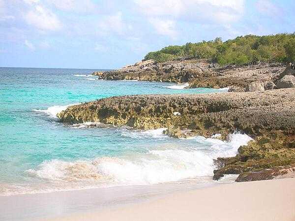 Anguilla, one of the Leeward Islands in the Caribbean, is composed of scrub-covered coral and limestone, which can be seen in this photograph of Limestone Bay. The island's many bays and pristine beaches draw visitors from around the world, making tourism Anguilla's main industry.