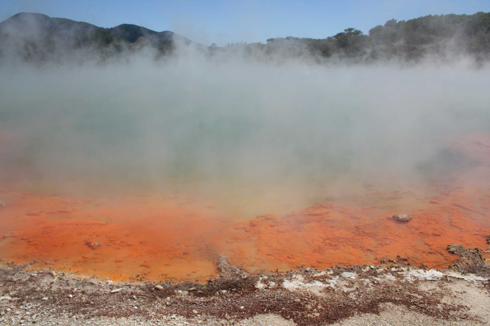 Champagne Pool, located in Wai-O-Tapu Thermal Park, is a large hot spring on New Zealand's North Island. Antimony-rich deposits around the rim turn the soil a bright orange color.